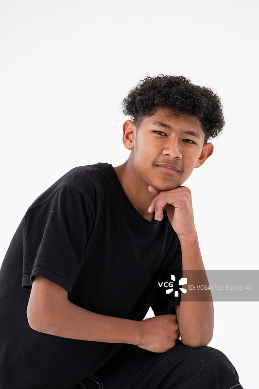 一位卷发黑色的小男孩在摄影棚中看着镜头图片素材