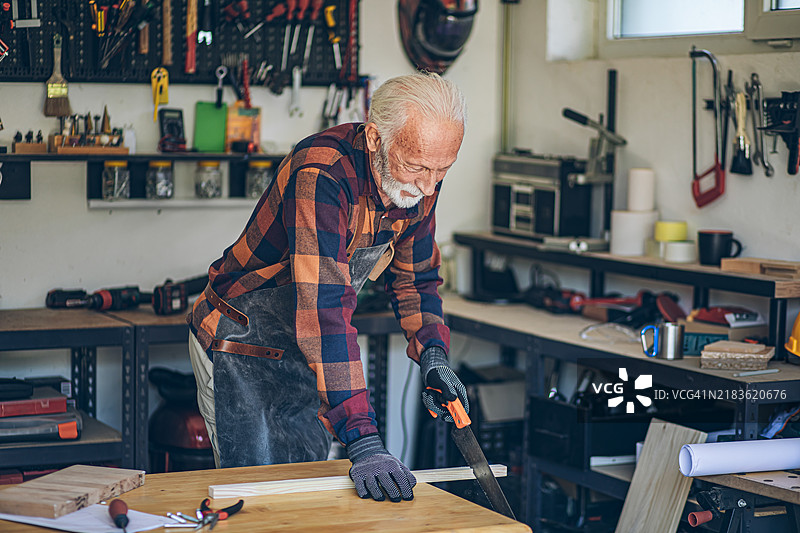 老年人正在用锯子切割木板图片素材