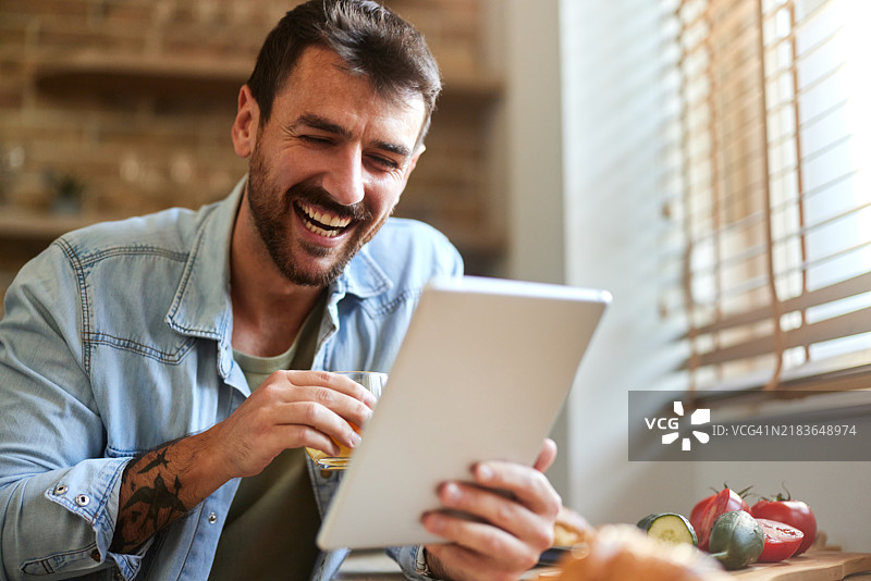 快乐的男人在餐厅用触控板上冲浪互联网。图片素材