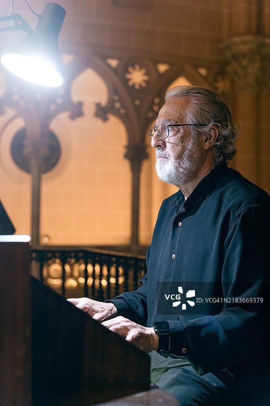 一位专注的老年风琴师在仔细跟随乐谱的同时演奏风琴图片素材