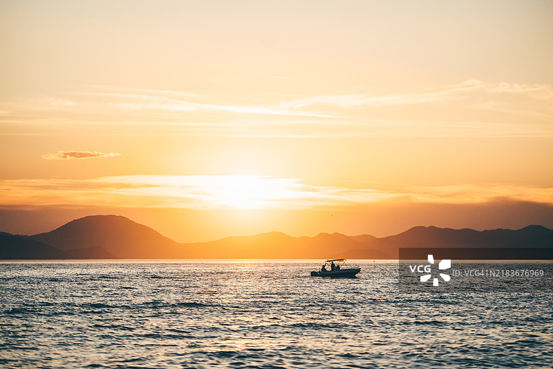 海上壮丽日落时的船只。图片素材