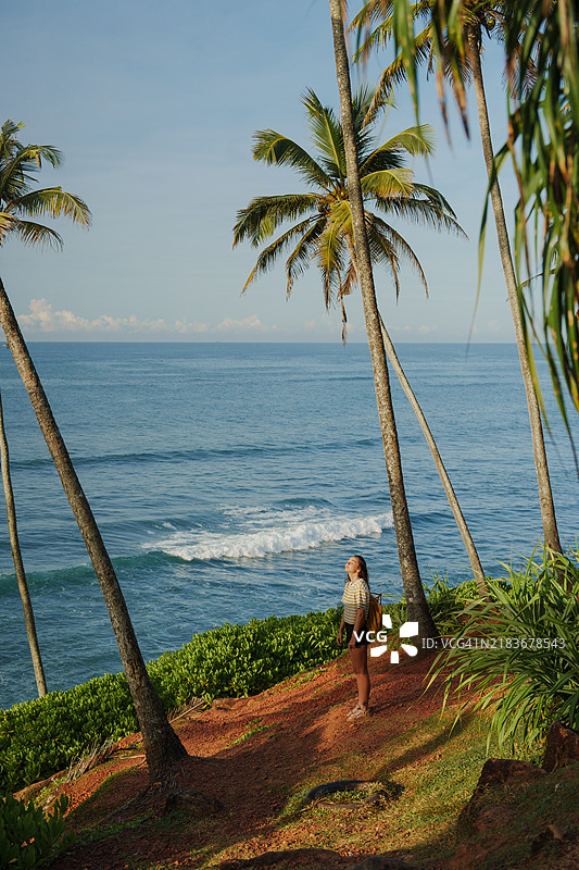 女人在棕榈树丛中凝视海洋图片素材