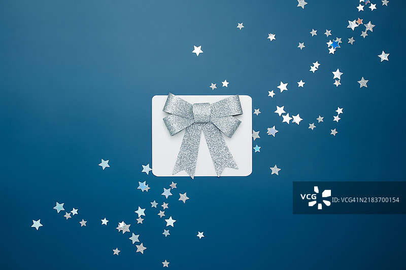 蓝色背景上的银色星星彩纸和闪亮的蝴蝶结图片素材