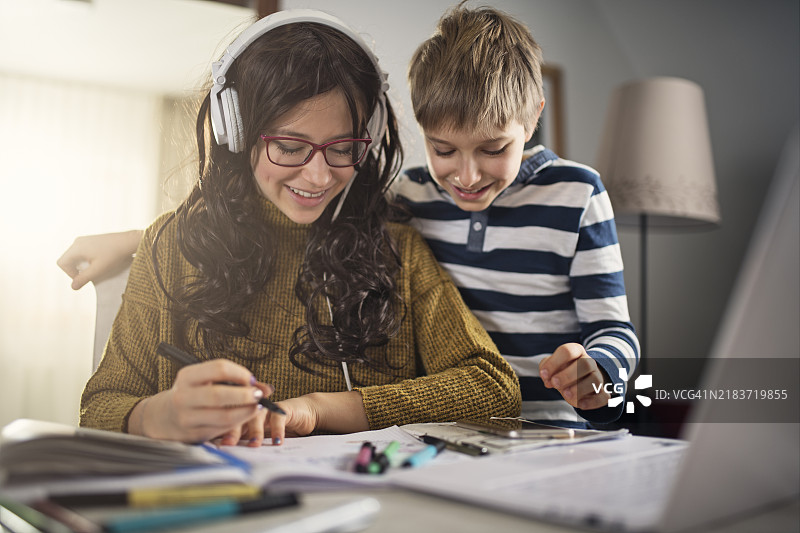 小男孩看着姐姐做作业。图片素材