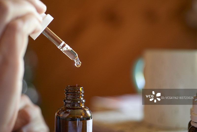滴管将液体滴入琥珀色瓶子的特写镜头图片素材