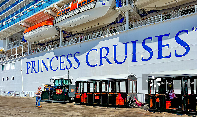 男子在纳皮尔拍摄沿路行驶的观光火车，旁边是皇冠公主号游轮。图片素材