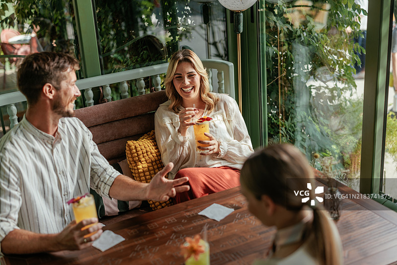 三个人坐在一个被绿植装饰的舒适咖啡馆里图片素材