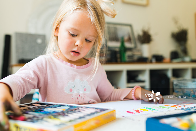 孩子在父亲的艺术工作室里用粉彩蜡笔。图片素材