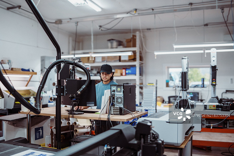 男性员工在工厂操作大型打印机和切纸机图片素材