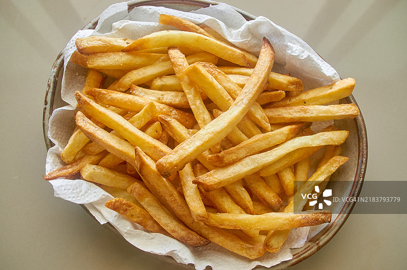 撒有牛至和盐的脆薯条放在吸油纸上，盛在大盘子里图片素材