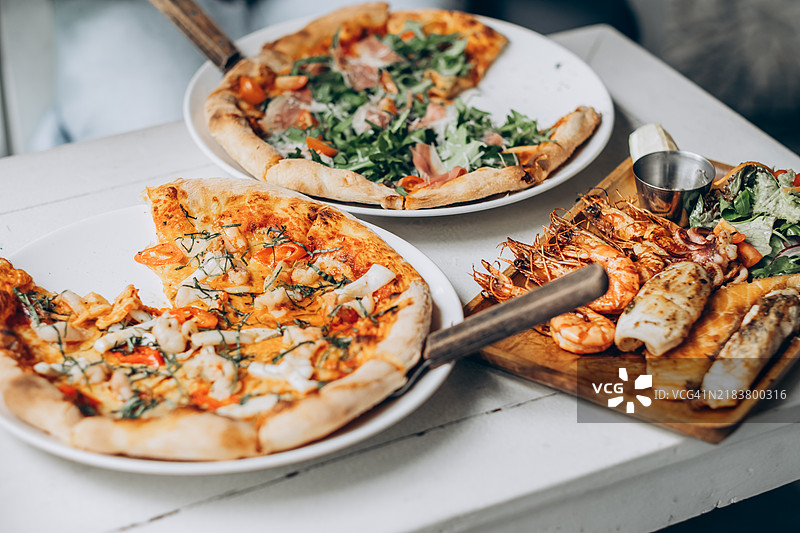 美味的意大利美食：披萨和海鲜拼盘，完美的用餐体验图片素材