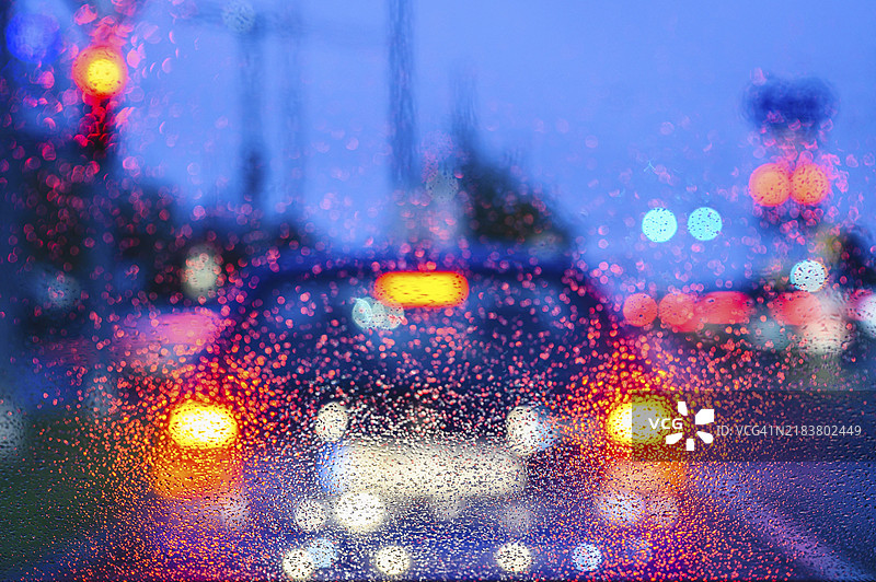 雨水浸湿的窗户透视夜晚模糊的车灯景象图片素材