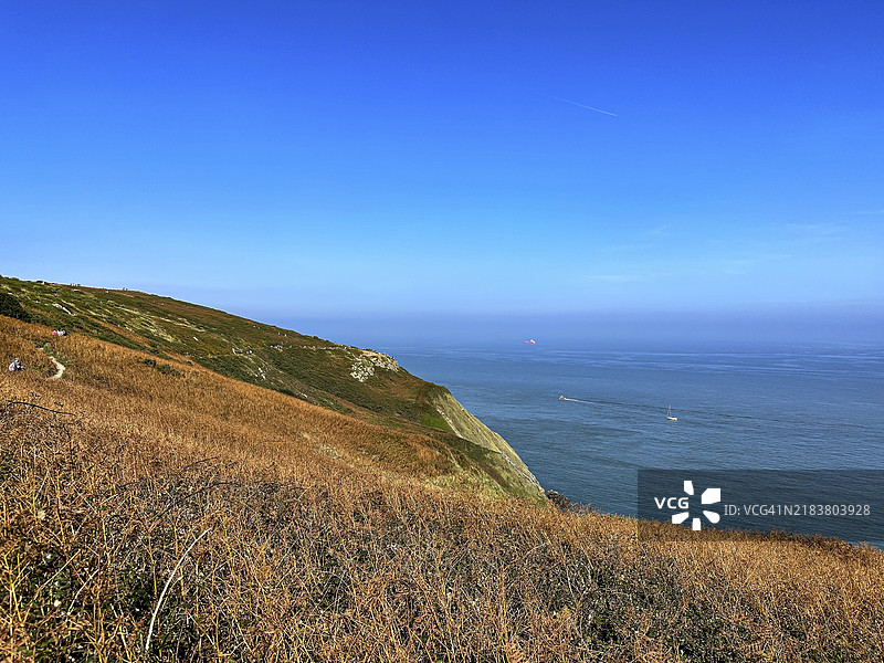 棕色山丘与蓝色海洋的景色，爱尔兰霍斯的海岸上，宁静的一天，天空晴朗。图片素材
