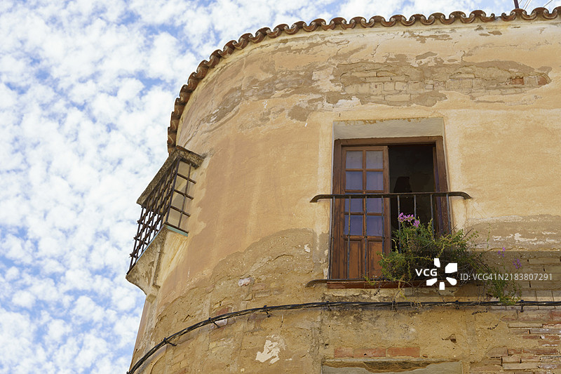 废弃建筑，外立面受损，阳台上长满植物，背景是蓝天和白云。图片素材