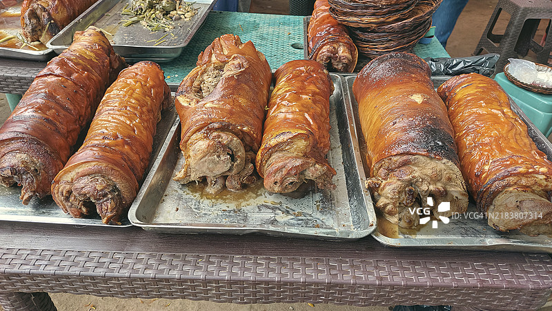 街头市场上展示的金棕色烤猪肉肚或烤猪肉，展现了菲律宾的传统美食和饮食文化。图片素材