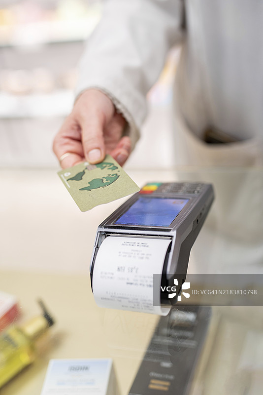 一只手将信用卡靠近数据终端进行刷卡交易图片素材