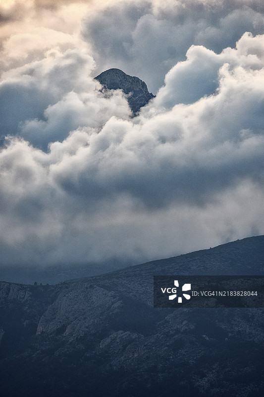 日落后，山顶透过蓬松的云朵（积云）图片素材