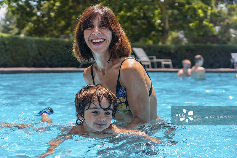 母亲和儿子在夏季假期的游泳池中学习游泳图片素材