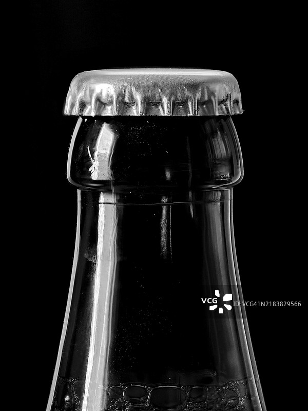 黑色背景下的啤酒瓶与瓶盖图片素材