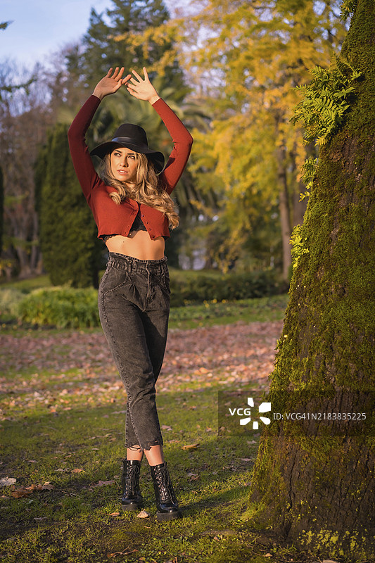 生活方式，日落时分在绿色公园里戴着黑色帽子的白人女孩肖像图片素材