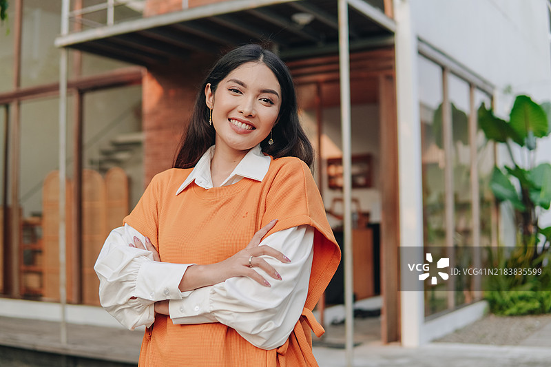自信的年轻亚洲女性微笑着，双臂交叉摆姿势。图片素材