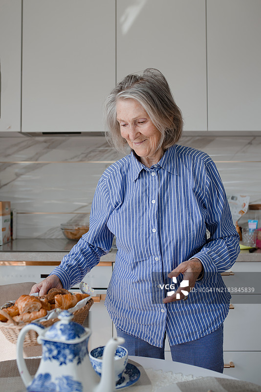 美丽的老妇人与可颂面包。图片素材