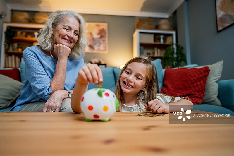 可爱的女孩正在往储蓄罐里投币图片素材