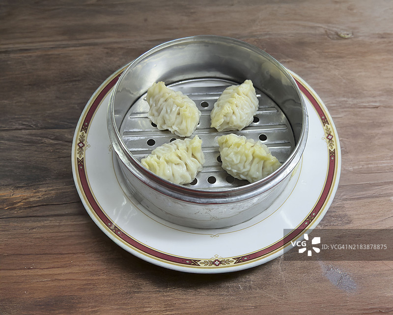 蒸盘上的鲨鱼鳍饺子放在木桌上图片素材