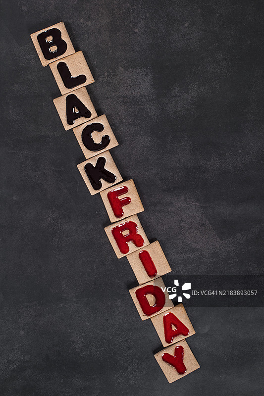 黑色星期五。方形饼干，黑色和红色果酱填充，形状为“黑色星期五”字样。深色背景。俯视图。图片素材