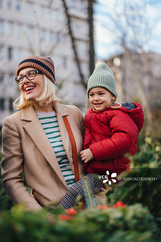 母亲和孩子享受节日庆祝活动，身边有圣诞树图片素材