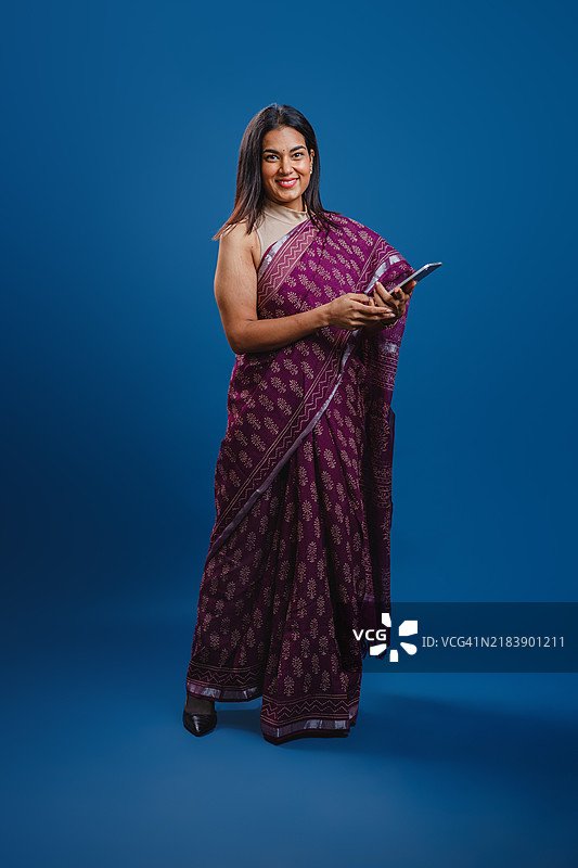 亚洲女商人在蓝色背景下手持手机的肖像图片素材