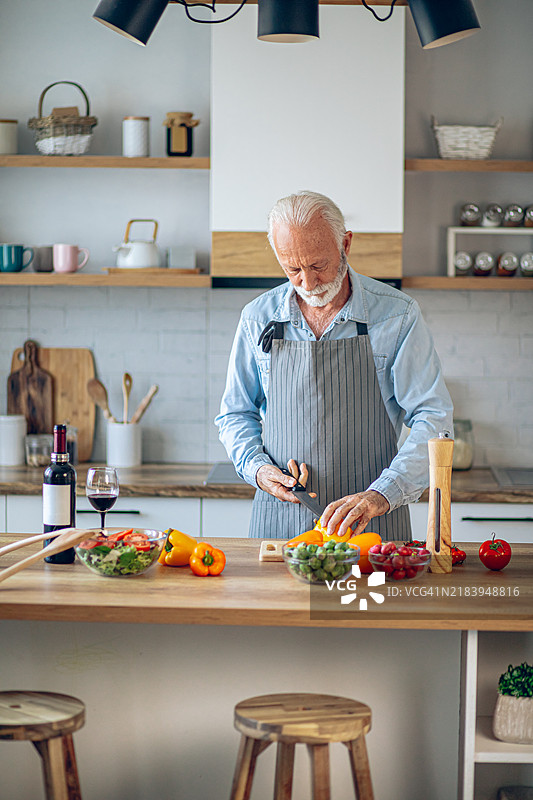 快乐的退休老人在厨房里做饭图片素材