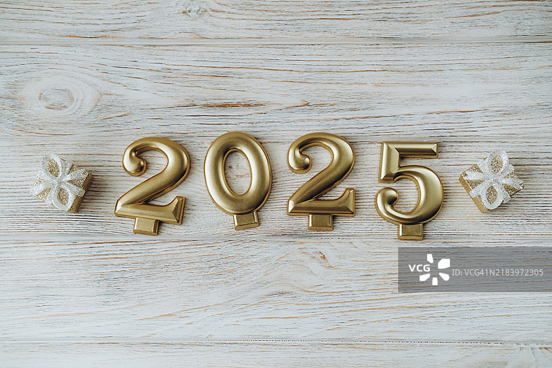金色的2025在木板上的玩具礼品盒之间。图片素材