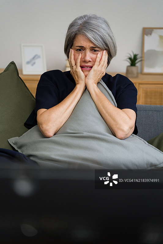 一位老年女性在家中观看令人震惊的电视节目图片素材