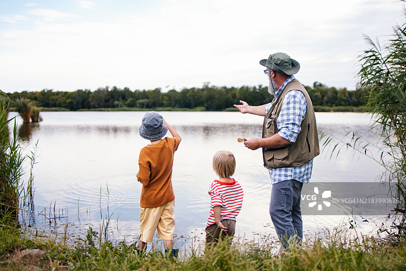 祖父和孙子们在湖边享受宁静的钓鱼日图片素材