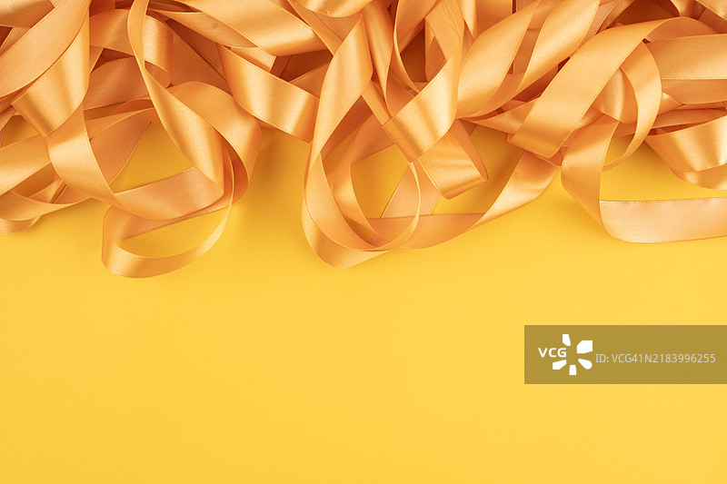 金色丝带在黄色背景上，留有空白位置。图片素材