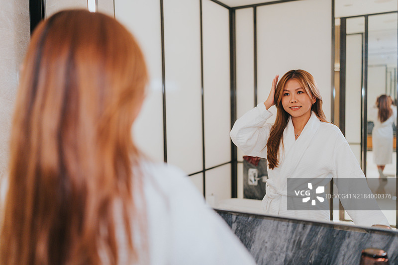 快乐的Z世代女孩们在中国大湾区珠海旅行。她们在酒店房间的浴室里卸妆，互相开玩笑。图片素材