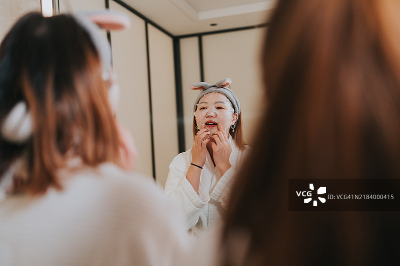 快乐的Z世代女孩们在中国大湾区珠海旅行。她们在酒店房间的浴室里卸妆，互相开玩笑。图片素材