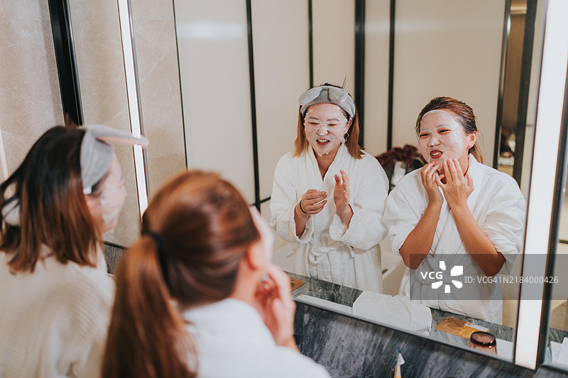 快乐的Z世代女孩们在中国大湾区珠海旅行。她们在酒店房间的浴室里卸妆，互相开玩笑。图片素材