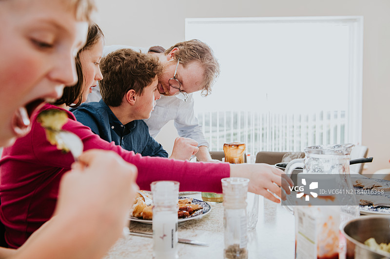 一家人在阳光明媚的下午聚在家中，共享美好的一餐，欢声笑语不断。图片素材