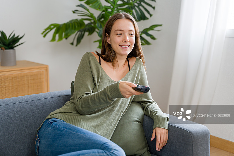 年轻女性在家中沙发上放松并观看电视图片素材