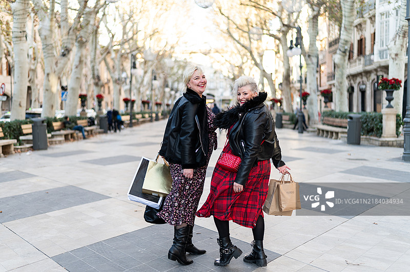 两位快乐的女性在圣诞购物后走在街上图片素材