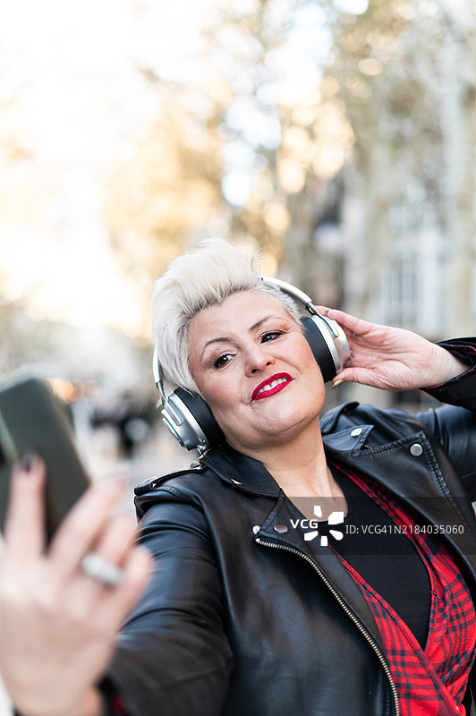 时尚的女性在户外享受音乐并自拍图片素材