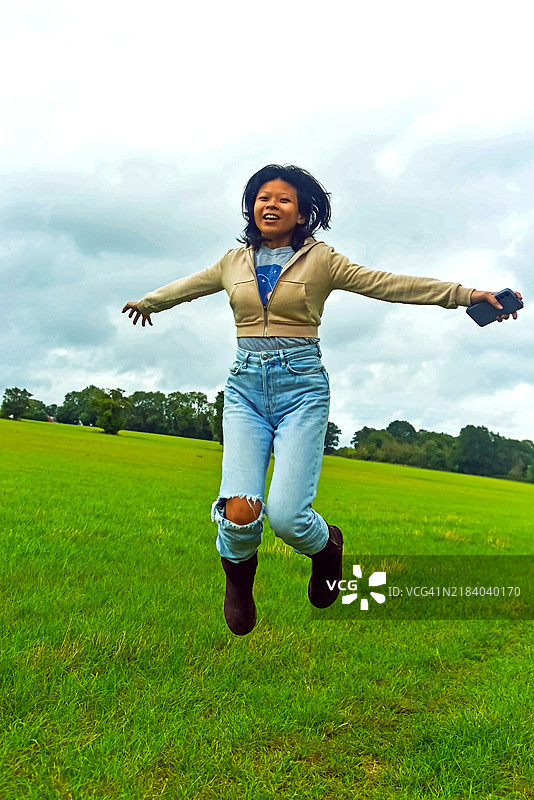 年轻的亚洲女性在阴天的农田上欢快地跳跃图片素材