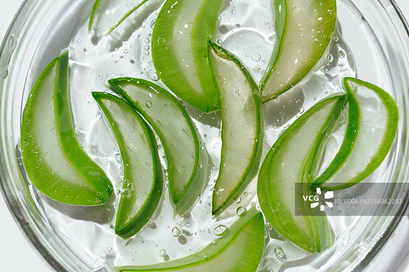 特写的培养皿，涂抹着化妆品凝胶，旁边有芦荟植物，背景为白色。化妆品化学实验室研究的概念。天然药物，有机美容产品。图片素材