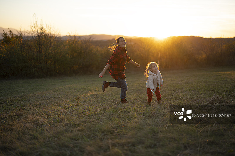 家庭在日落时分在大自然中放风筝。图片素材