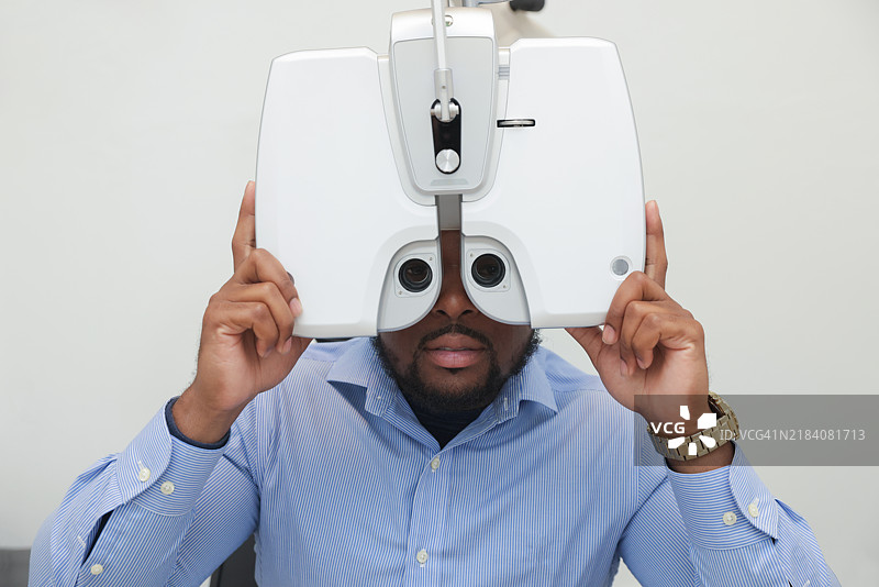 一位穿着休闲服的非裔美国男性患者正在进行眼科检查。图片素材