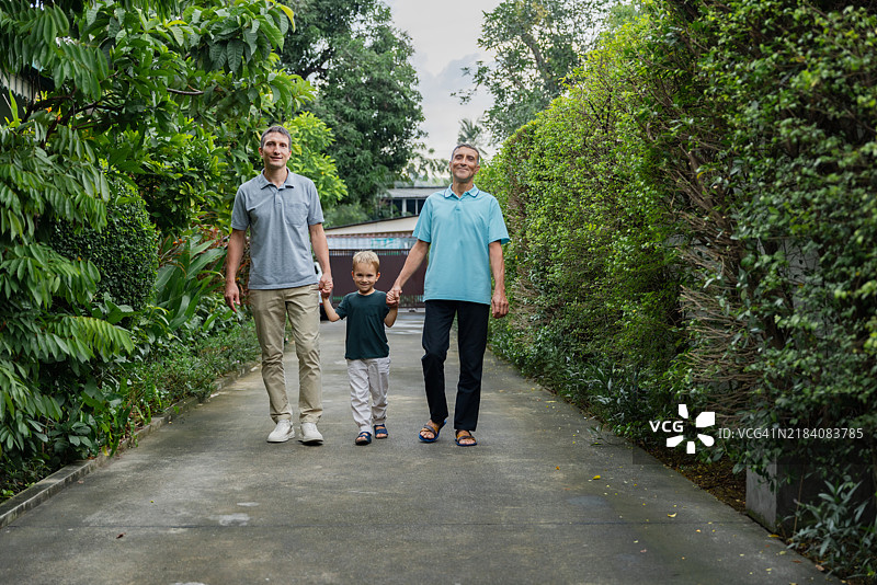 家庭在郊区社区的绿意盎然的小路上享受阳光散步图片素材