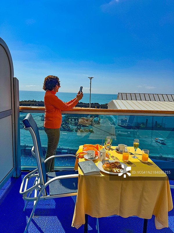 乘客在阳台上站着，享用完阳台早餐后，拍摄纳皮尔邮轮的到来。图片素材