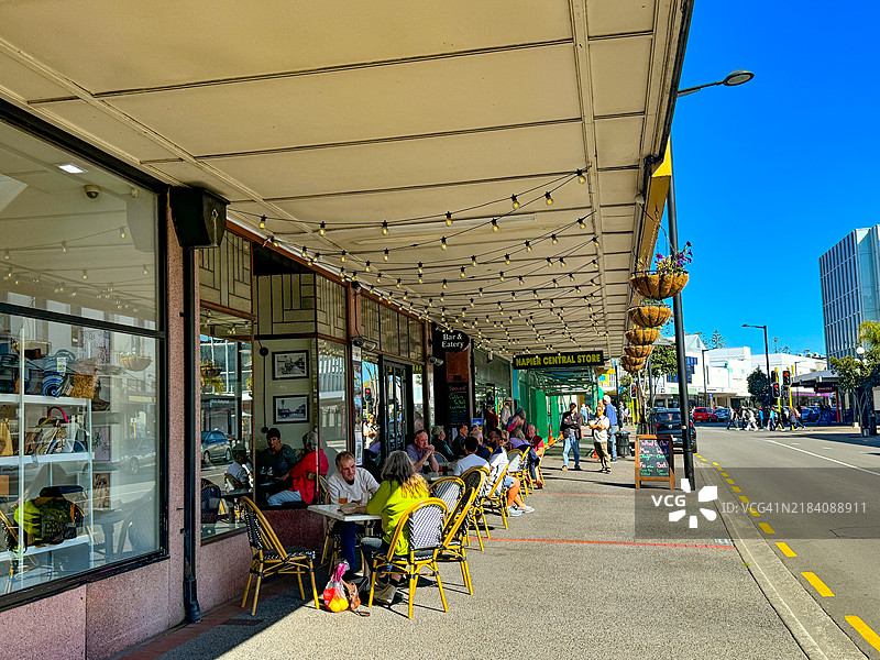 新西兰纳皮尔市中心咖啡馆外的桌子旁坐着的人们图片素材